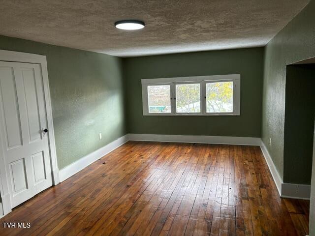 spare room with a textured ceiling and dark hardwood / wood-style floors