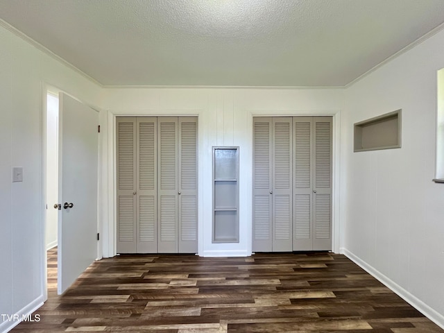 unfurnished bedroom featuring a textured ceiling, dark hardwood / wood-style floors, and crown molding