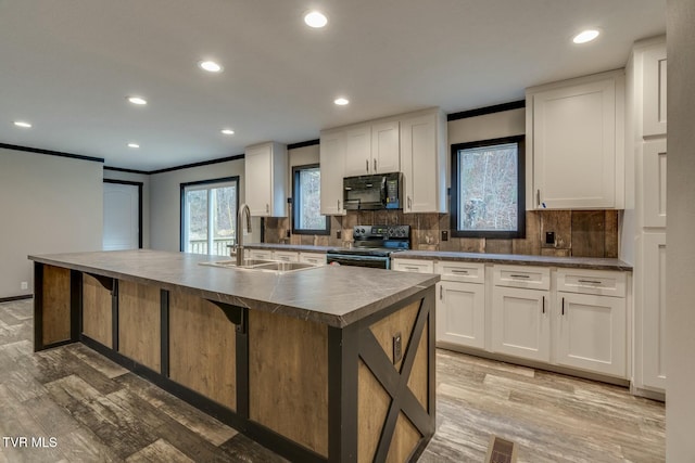 kitchen featuring white cabinetry, sink, a kitchen island with sink, and black appliances