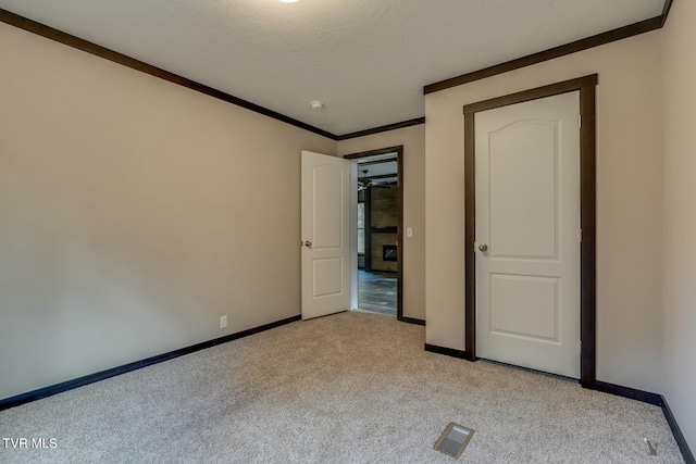 unfurnished bedroom with ornamental molding, light carpet, and a textured ceiling