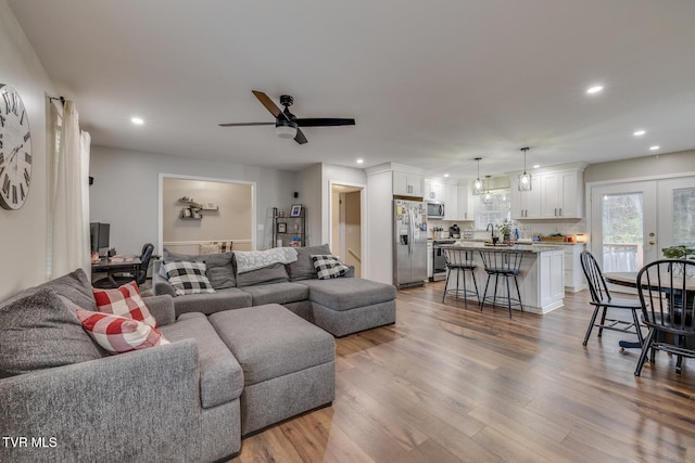 living room featuring ceiling fan, sink, wood-type flooring, and french doors