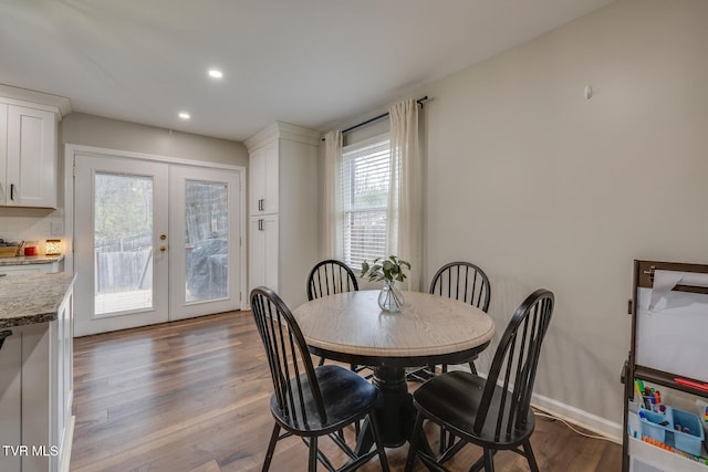 dining room featuring a healthy amount of sunlight, wood-type flooring, and french doors