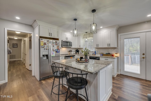 kitchen featuring white cabinetry, a center island, stainless steel appliances, light hardwood / wood-style floors, and decorative backsplash