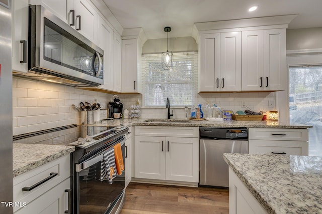 kitchen with backsplash, sink, white cabinets, and stainless steel appliances