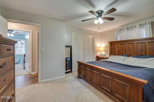 carpeted bedroom with ceiling fan, a textured ceiling, and a closet