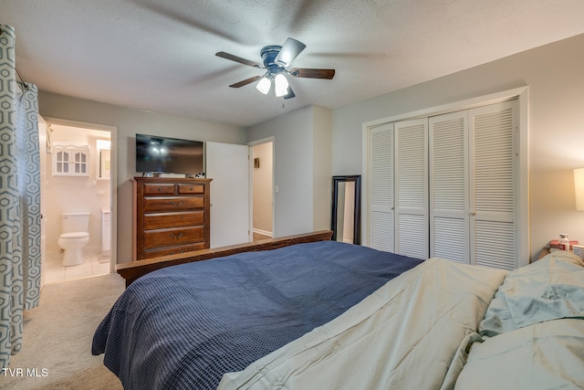 bedroom with ceiling fan, a textured ceiling, connected bathroom, light colored carpet, and a closet