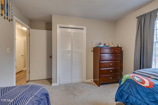 bedroom with a textured ceiling, light colored carpet, and a closet