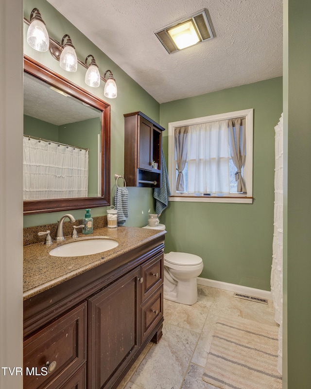 bathroom with vanity, toilet, and a textured ceiling