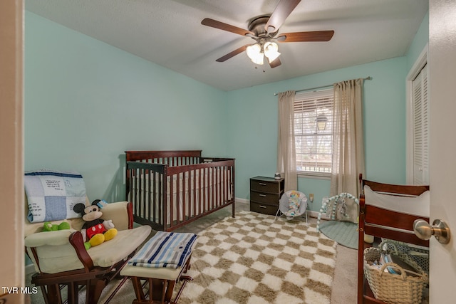 carpeted bedroom with ceiling fan and a crib