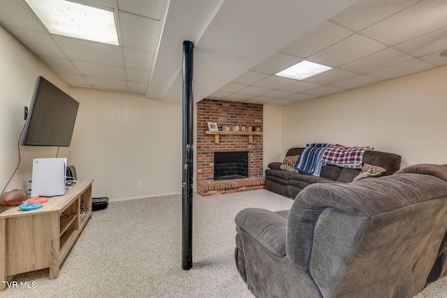 carpeted living room featuring a drop ceiling and a brick fireplace