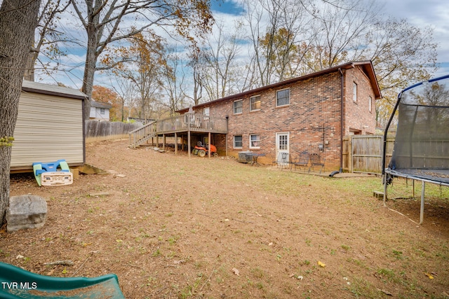 back of house with a trampoline and a wooden deck