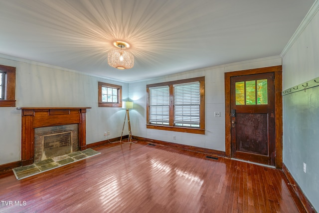 unfurnished living room with hardwood / wood-style floors, crown molding, and a tile fireplace