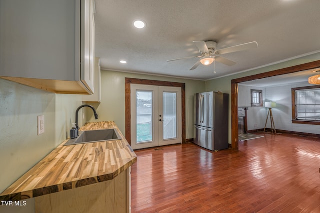 kitchen with french doors, crown molding, sink, wood-type flooring, and stainless steel refrigerator