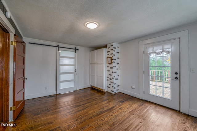 foyer with dark hardwood / wood-style floors, a barn door, and a textured ceiling