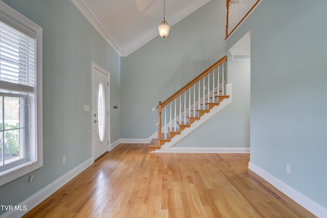 foyer featuring vaulted ceiling, light hardwood / wood-style flooring, and ornamental molding