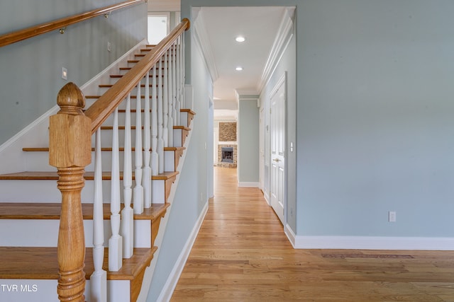 stairway featuring a fireplace, ornamental molding, and hardwood / wood-style flooring