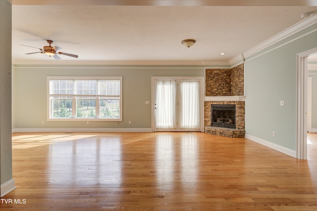 unfurnished living room featuring ceiling fan, crown molding, light hardwood / wood-style floors, a textured ceiling, and a fireplace