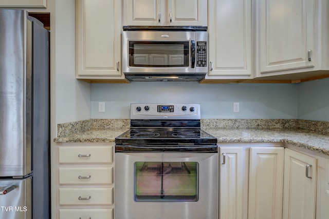 kitchen with light stone countertops, stainless steel appliances, and white cabinets