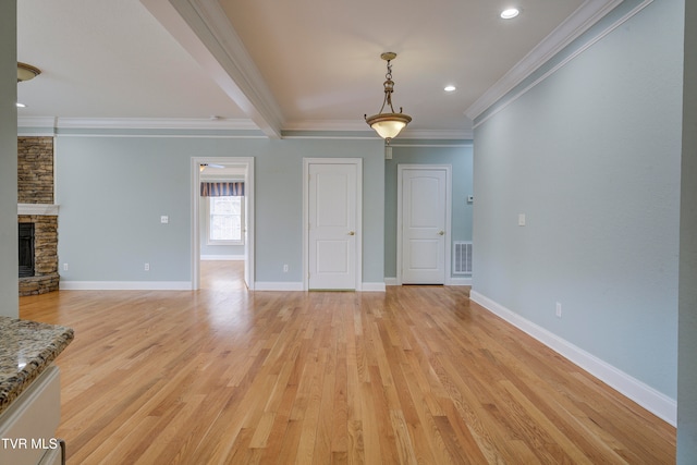 unfurnished living room featuring beamed ceiling, light hardwood / wood-style flooring, a stone fireplace, and crown molding