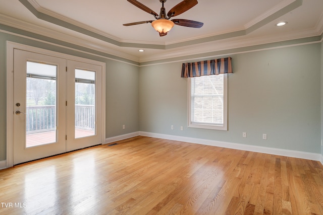 spare room with ceiling fan, light hardwood / wood-style floors, crown molding, and a tray ceiling