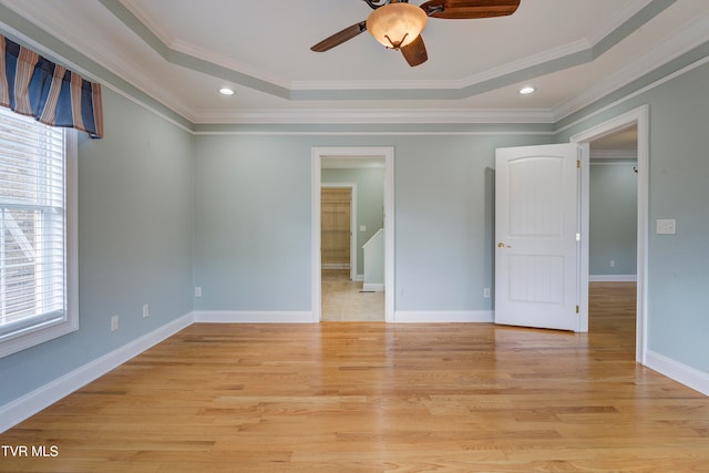 unfurnished bedroom featuring light wood-type flooring, a raised ceiling, ceiling fan, and ornamental molding