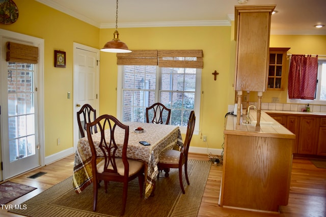 dining area featuring plenty of natural light, ornamental molding, and light hardwood / wood-style flooring