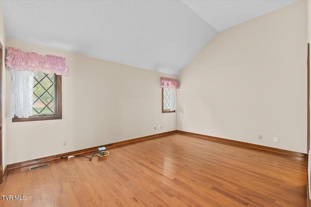 empty room featuring wood-type flooring and vaulted ceiling