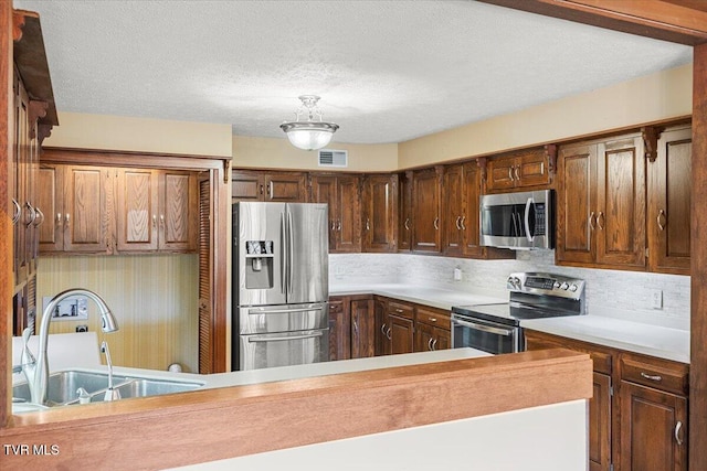 kitchen featuring a textured ceiling, stainless steel appliances, and sink