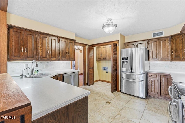 kitchen with a textured ceiling, stainless steel appliances, backsplash, and sink