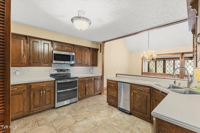 kitchen with a textured ceiling, hanging light fixtures, sink, and appliances with stainless steel finishes