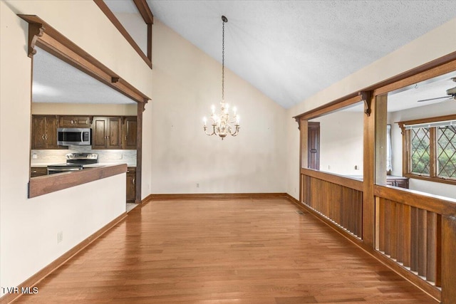 unfurnished dining area with a textured ceiling, high vaulted ceiling, a notable chandelier, and light wood-type flooring