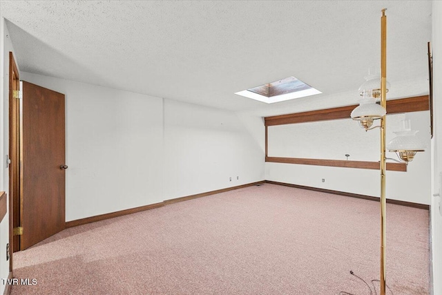 additional living space with a textured ceiling, light carpet, and a skylight