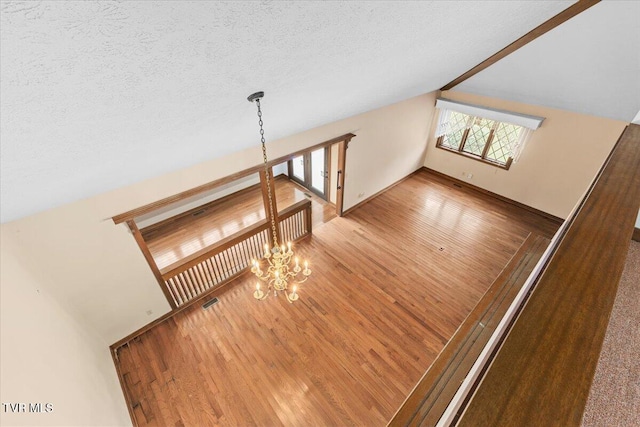 stairway featuring hardwood / wood-style floors, vaulted ceiling with beams, a textured ceiling, and an inviting chandelier