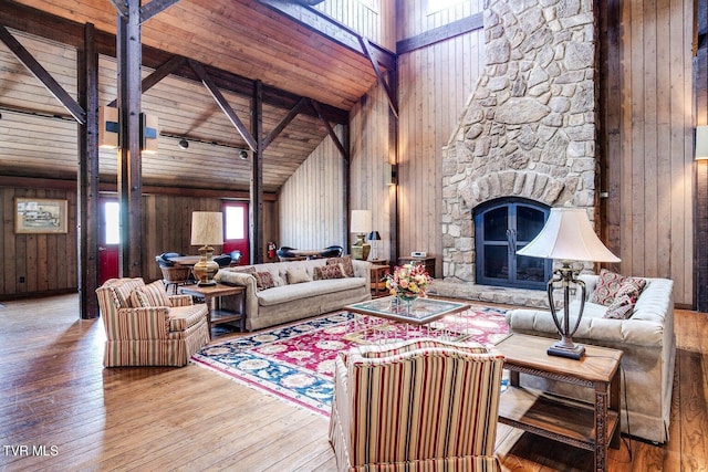 living room with high vaulted ceiling, wooden walls, a fireplace, wood ceiling, and hardwood / wood-style flooring