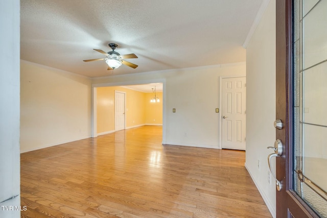 spare room with ceiling fan with notable chandelier, ornamental molding, a textured ceiling, and light wood-type flooring