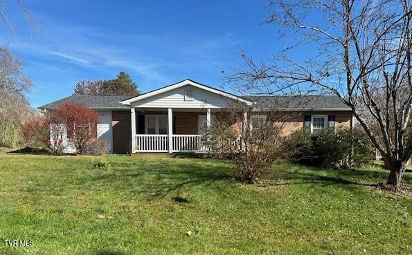 single story home with a porch and a front lawn