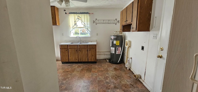 kitchen featuring a textured ceiling, electric water heater, ceiling fan, and sink