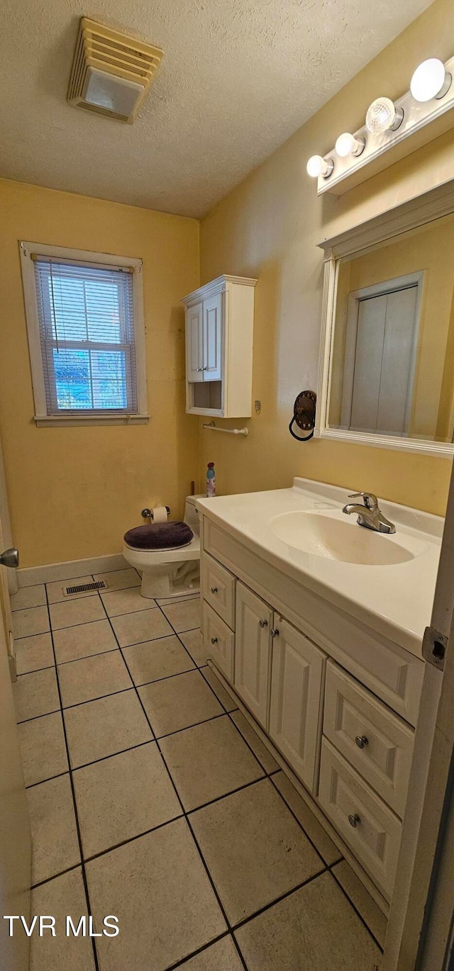 bathroom featuring tile patterned floors, vanity, a textured ceiling, and toilet