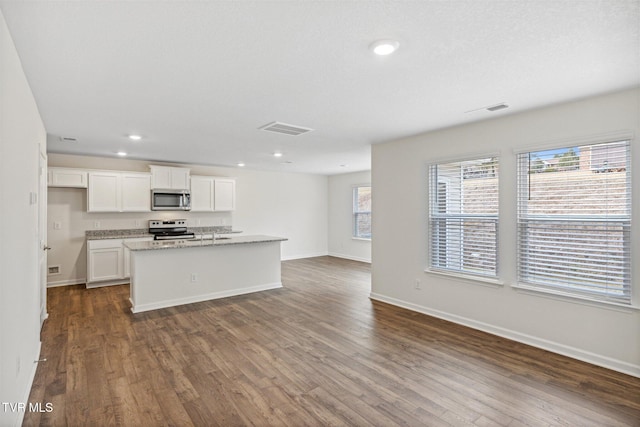 kitchen featuring a kitchen island with sink, dark hardwood / wood-style floors, stainless steel appliances, and white cabinetry