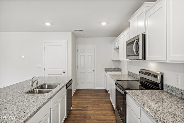 kitchen with white cabinets, appliances with stainless steel finishes, sink, and light stone counters