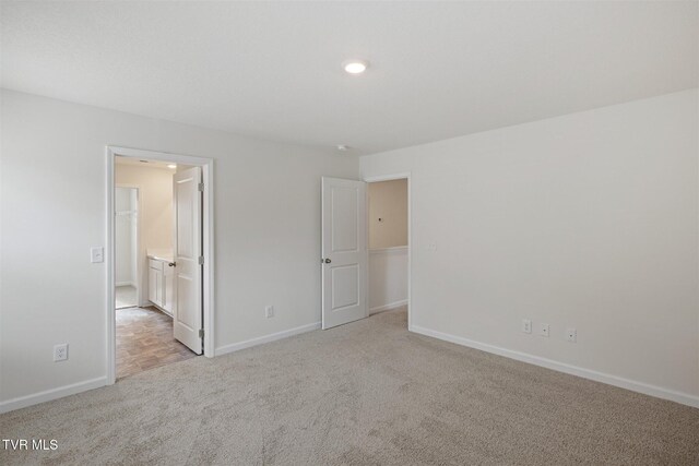 unfurnished bedroom featuring light carpet and ensuite bathroom