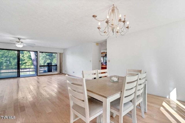 dining area with ceiling fan with notable chandelier, a textured ceiling, and light wood-type flooring