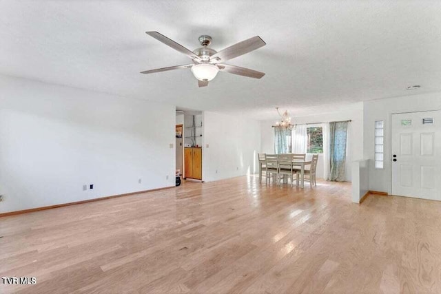 unfurnished living room with ceiling fan with notable chandelier, light wood-type flooring, and a textured ceiling