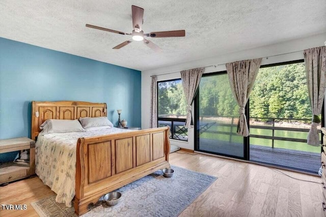 bedroom featuring access to exterior, light hardwood / wood-style flooring, and a textured ceiling