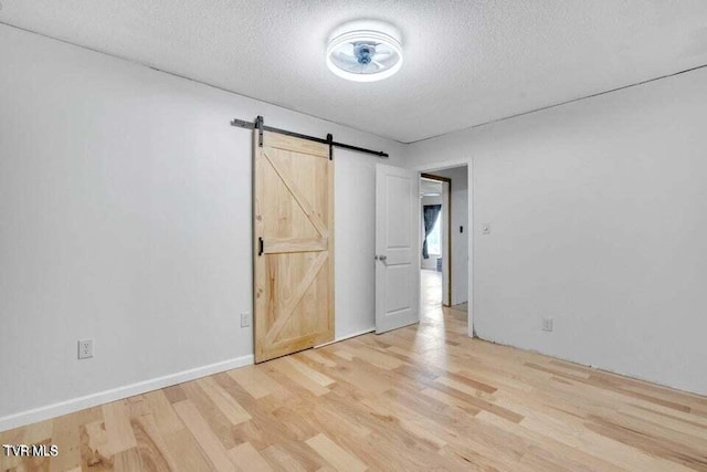 unfurnished bedroom with a barn door, a textured ceiling, and hardwood / wood-style flooring