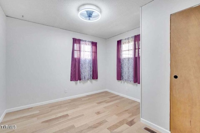 unfurnished room featuring a textured ceiling and light hardwood / wood-style flooring