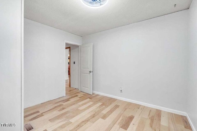 unfurnished room featuring light hardwood / wood-style flooring and a textured ceiling