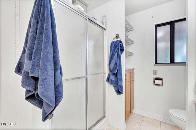 bathroom featuring tile patterned floors, toilet, a shower with shower door, and a textured ceiling