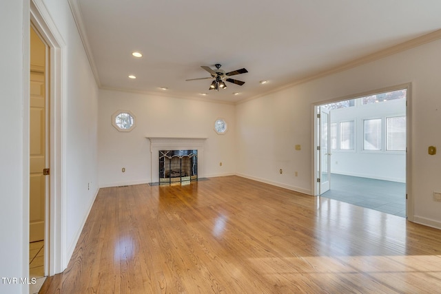 unfurnished living room with ceiling fan, crown molding, light wood-type flooring, and a fireplace