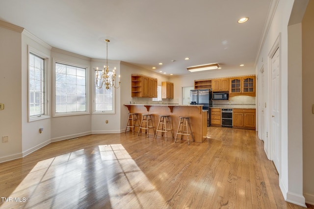 kitchen with kitchen peninsula, light hardwood / wood-style flooring, a breakfast bar, and ornamental molding